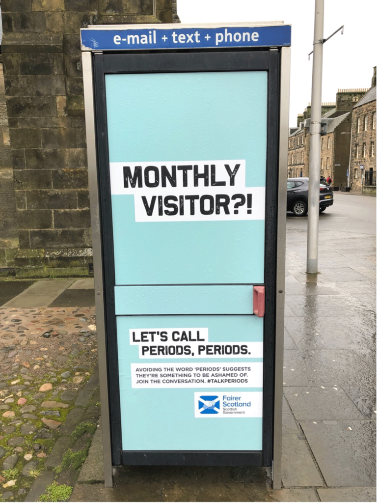 Image of a phone box in St Andrews with a campaign poster saying "monthly visitor"
